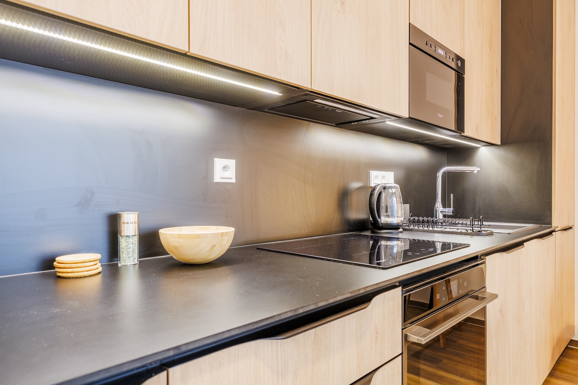 Plně vybavená kuchyně apartmánu s indukční varnou deskou, troubou a digestoří