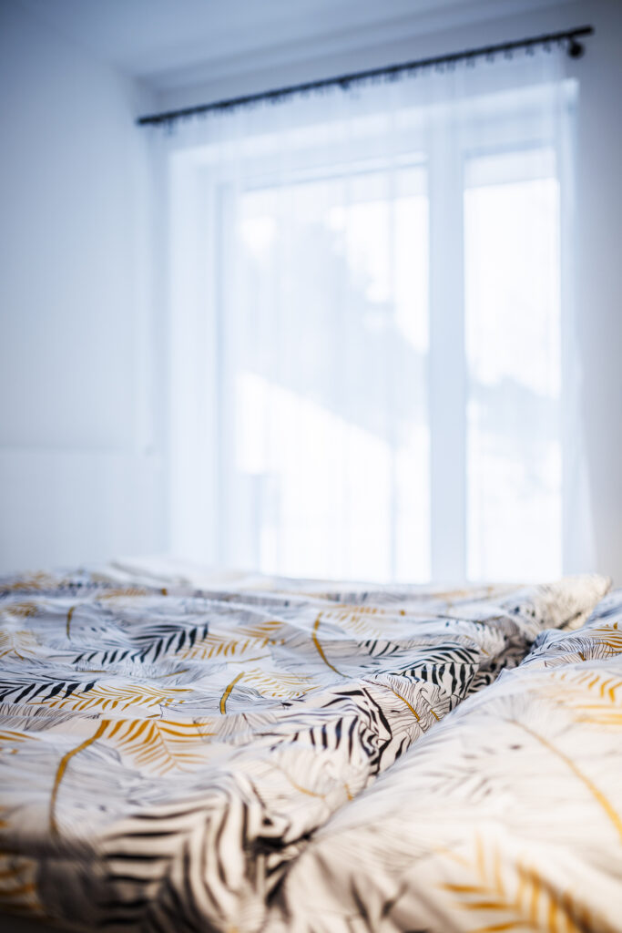 Ložnice – detail povlečení u okna s denním světlem (Apartmán Soňa Dolní Morava)