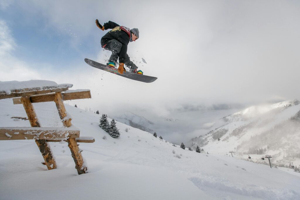 Snowboardista skákající na sjezdovce v zasněžené horské krajině